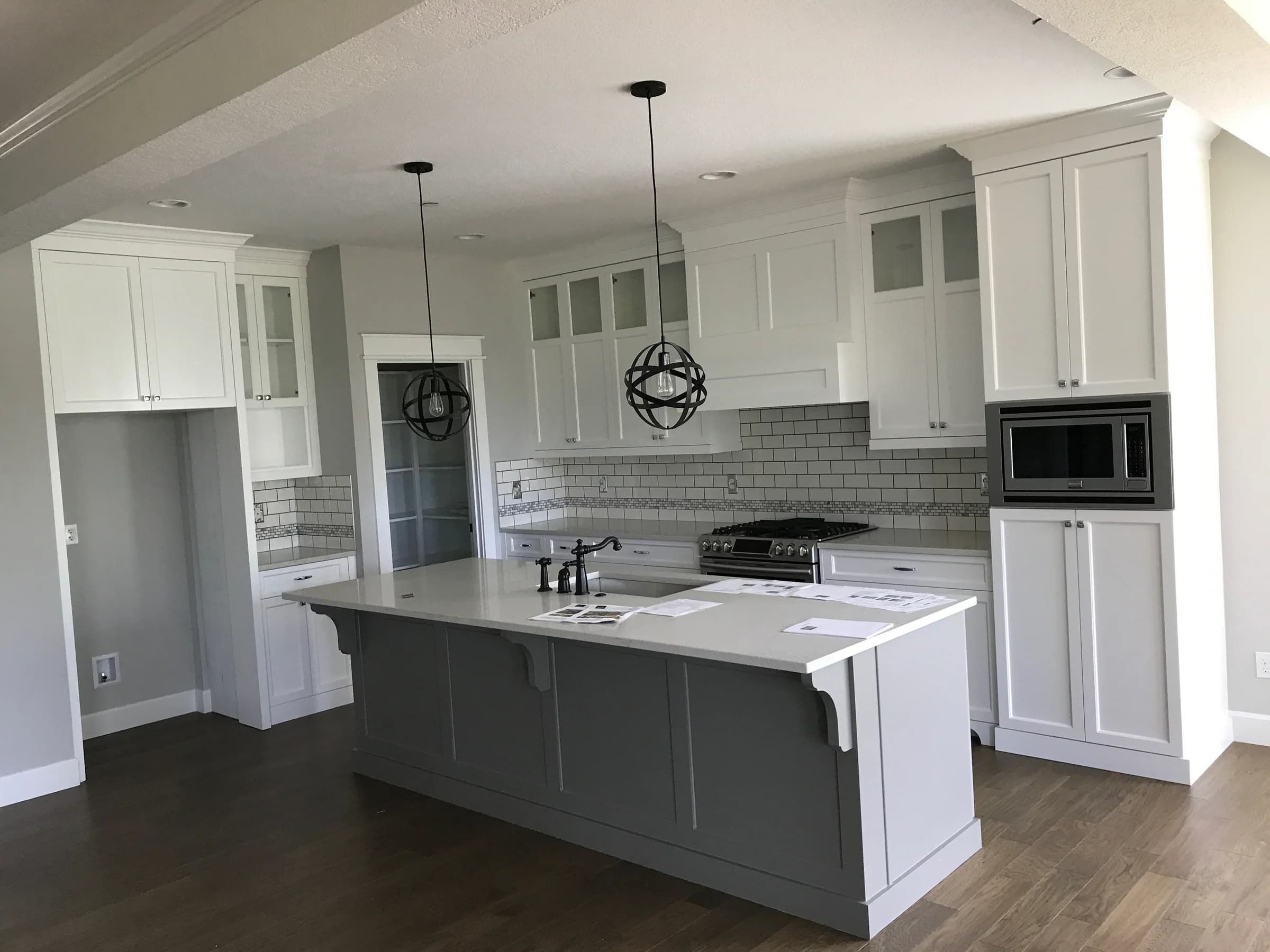 NS Wood Finishing project: white framed kitchen cabinets surrounding a gray island