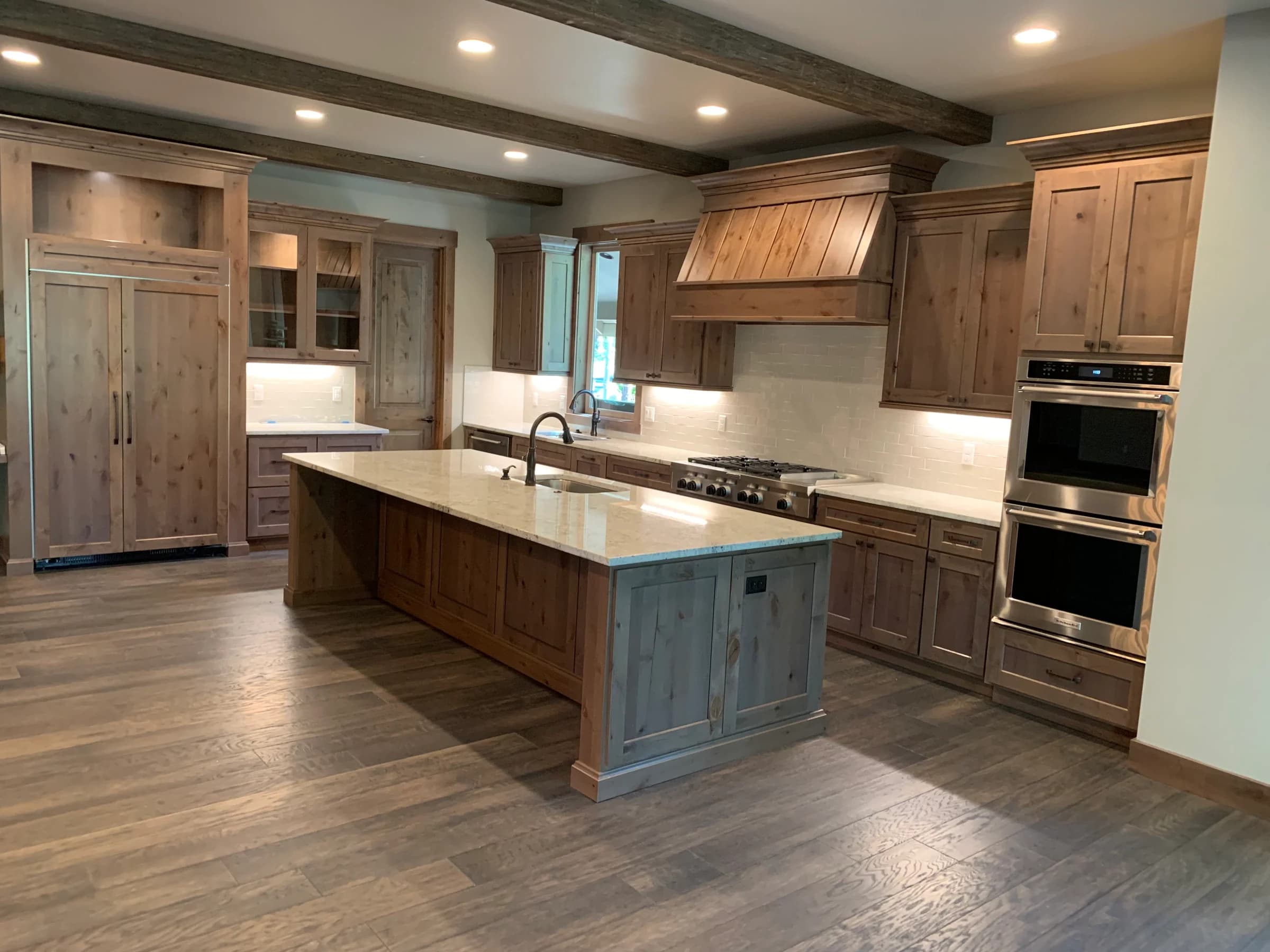 NS Wood Finishing project: wood cabinetry with a matching range hood, glass-front doors and a large island