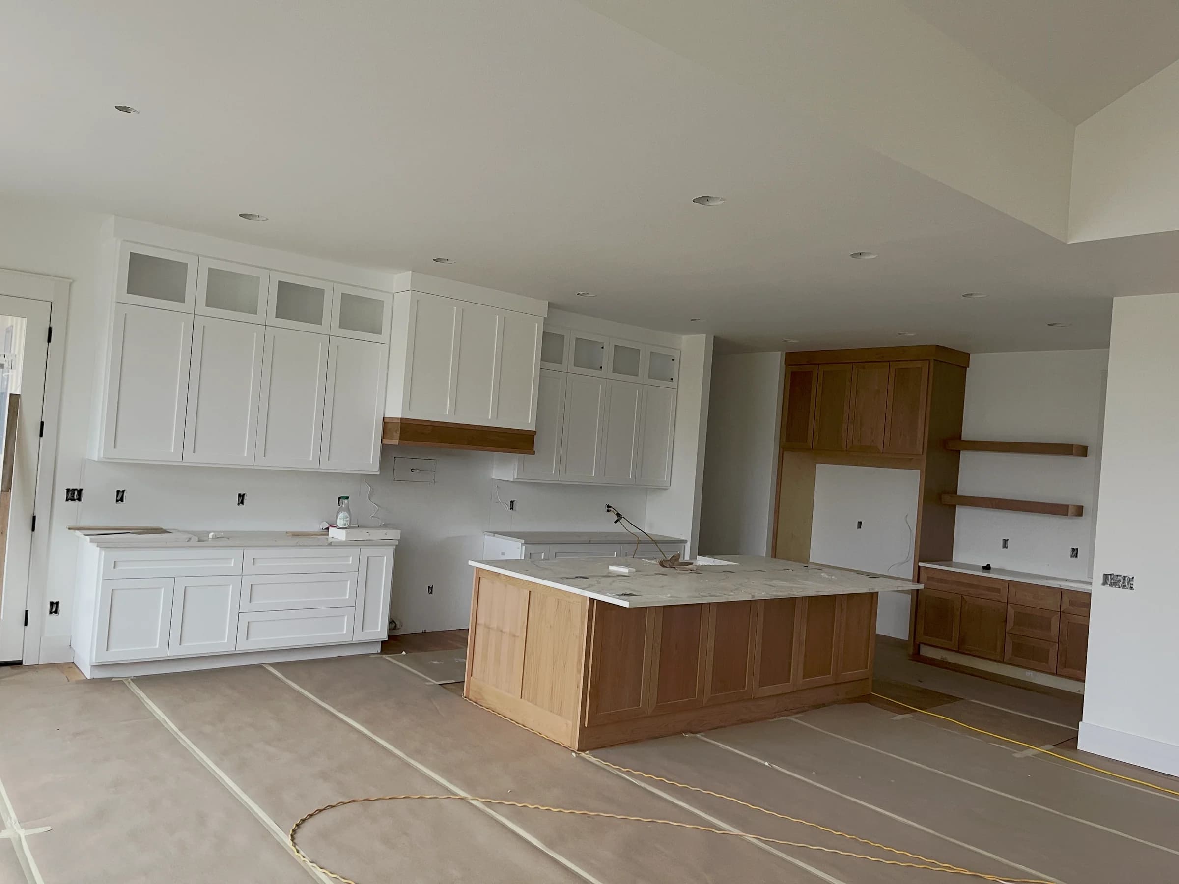 NS Wood Finishing project: a kitchen in progress with white cabinetry, a wood island and protected floors