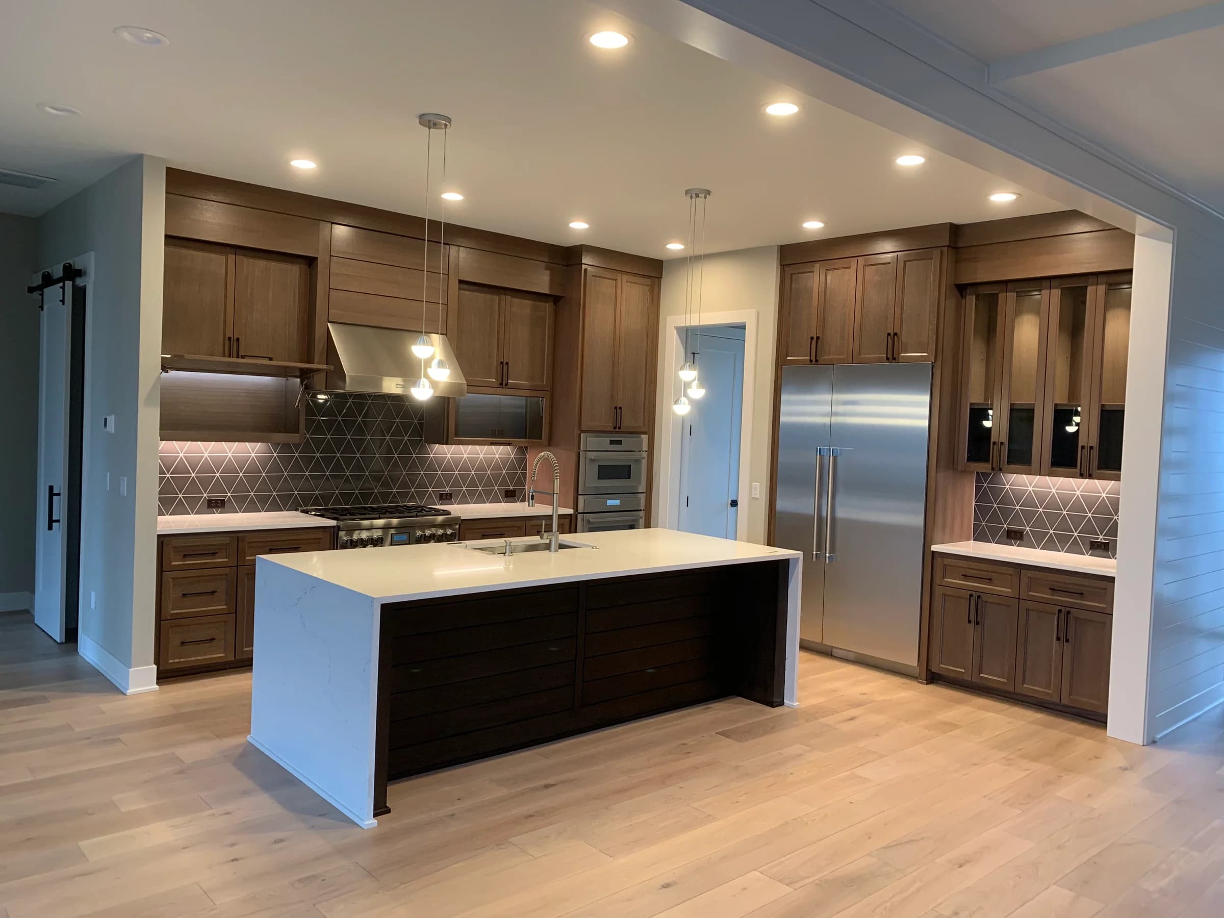 NS Wood Finishing project: rich brown kitchen cabinetry with a dark island and pale waterfall countertop