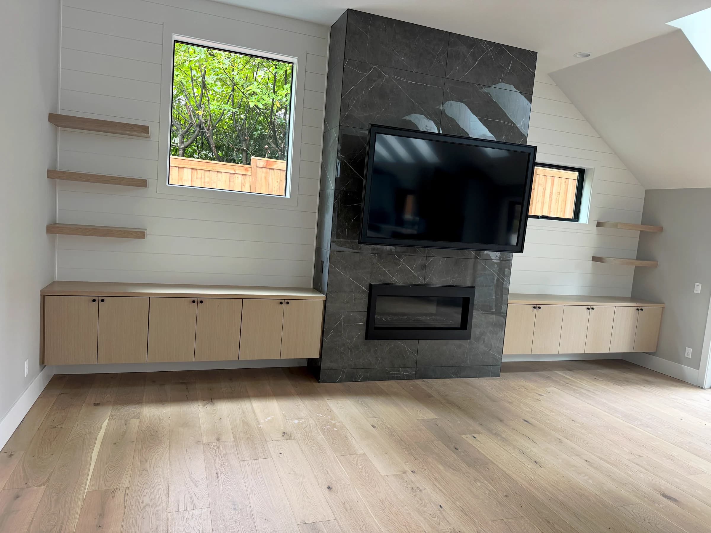 NS Wood Finishing project: wood media-room cabinets and floating shelves on either side of a dark fireplace